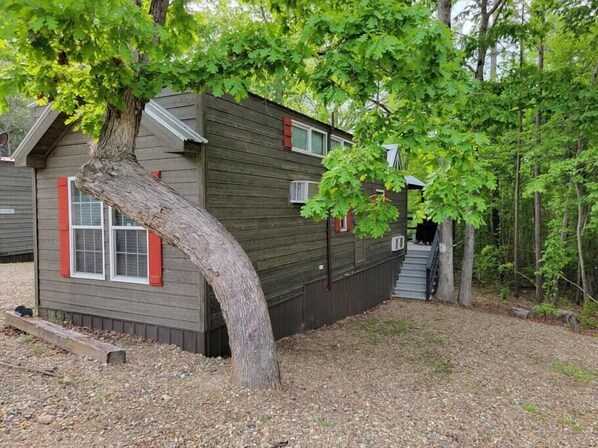 A small cabin with a sloped roof, a front porch, and a tree in front. - Juniper: Sleep 5, Tiny Cabin, Pets, Near Park/Lake (Broken Bow)