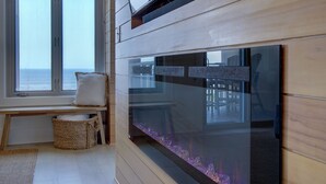 Une chambre moderne avec un grand aquarium en verre, un banc doté d’un coussin et une vue sur la mer par la fenêtre.
