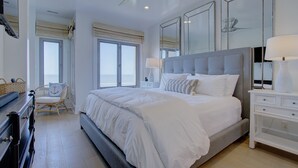 Une chambre à coucher moderne avec un grand lit, un ventilateur de plafond et une table de chevet avec une lampe.