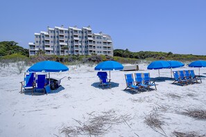 Ein Strandhotel mit mehreren blauen Sonnenschirmen und Liegestühlen.