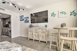 Una cocina moderna con electrodomésticos de acero inoxidable, un mueble blanco con motivos de tortuga y un televisor de pantalla plana montado en la pared.