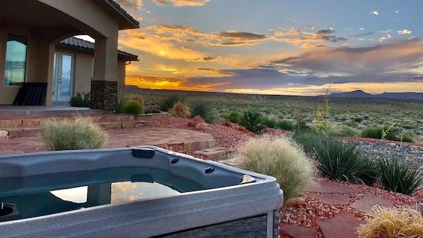 A hot tub in a landscaped garden with a view of a desert landscape and mountains in the distance. - Luxury Near Lake Powell & Antelope Canyon: Hot Tub, Views & EV Charger (Page)