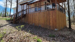 Una baita di legno con un balcone, una scala e un piccolo tavolo in primo piano.
