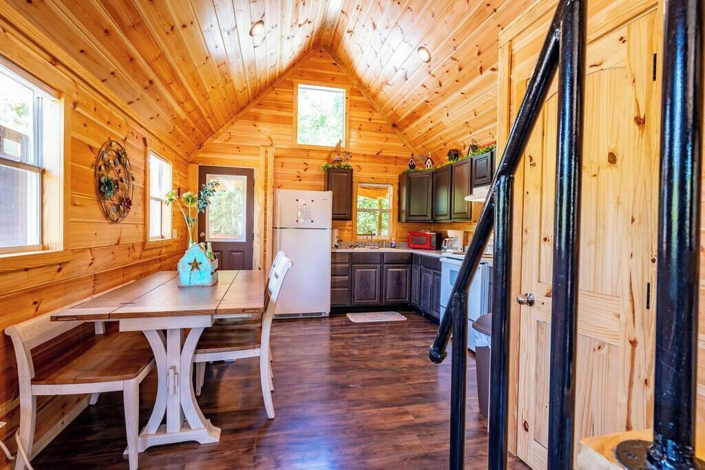 L’intérieur d’une cabane en bois comprend une table à manger, des chaises, un réfrigérateur, des placards et un escalier.