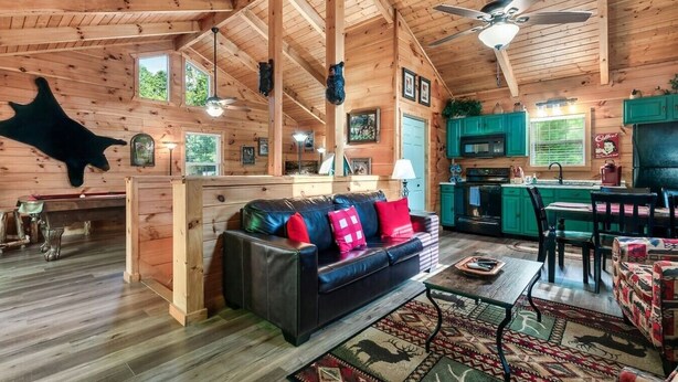 Interior de una cabaña de troncos con sala de estar, cocina y comedor.