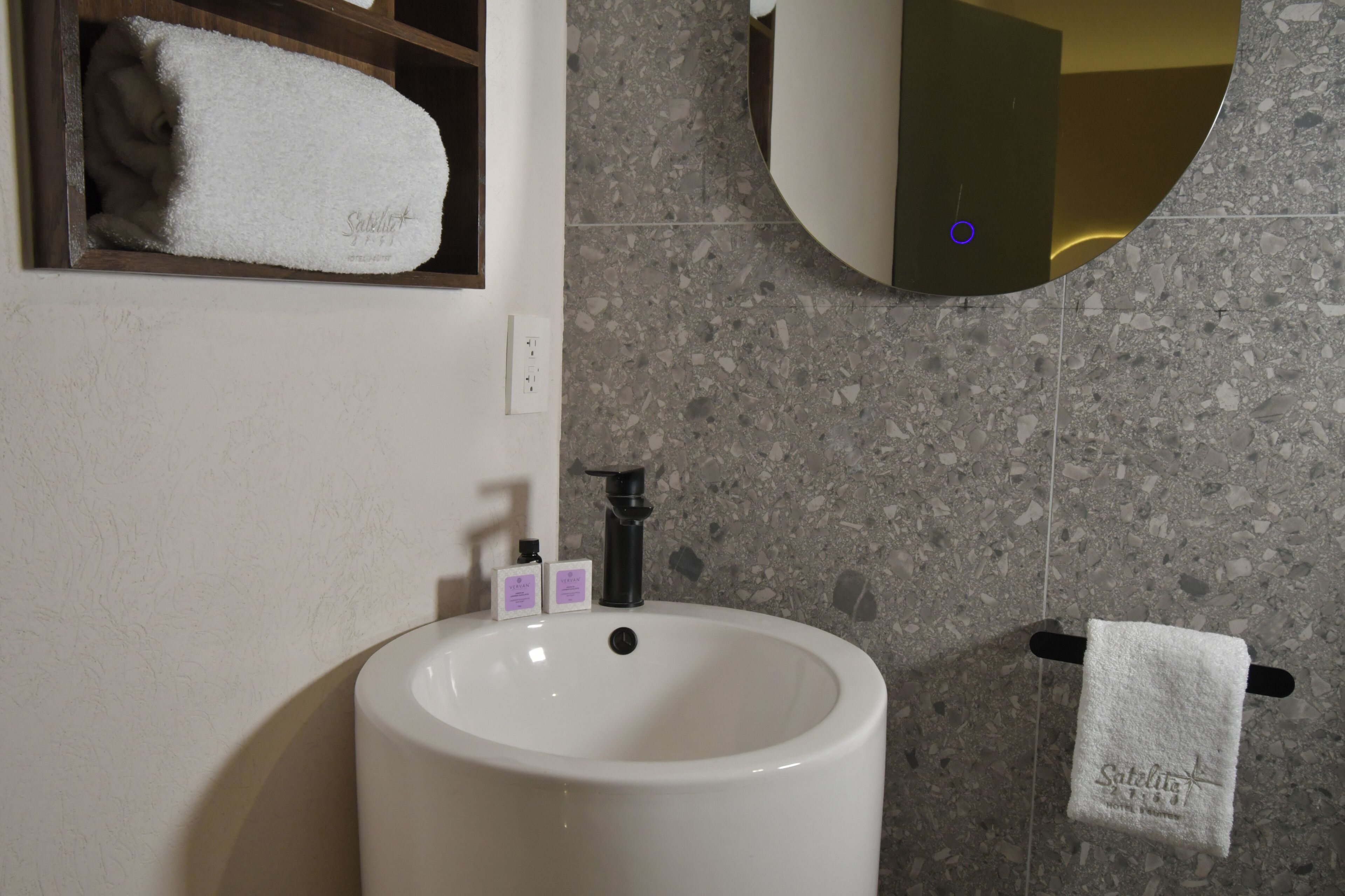 Une salle de bain avec un lavabo blanc, un miroir et un porte-serviettes sur lequel est posée une serviette blanche.