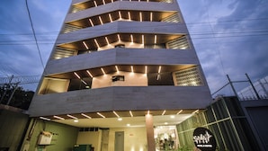 Een hotel met meerdere verdiepingen, met een modern design, voorzien van balkons en een bord waarop staat dat het een hotel met suites is.