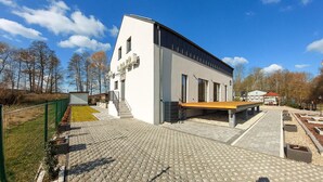 Un bâtiment moderne doté d’un toit plat, de grandes fenêtres et d’une cour dallée.
