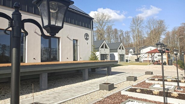 Un quai de gare avec un banc, un lampadaire et un bâtiment orné d’une horloge et d’un logo représentant un arbre.