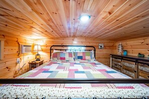 Cozy bedroom with a large bed, bedside lamp, and table with a lamp, offering a view of the outdoors.
