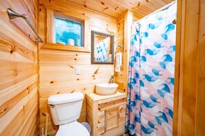 Bathroom features a toilet, sink, and shower with a geometric-patterned curtain.