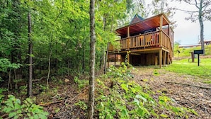Eine Holzhütte mit einem Balkon, umgeben von dichtem Wald.