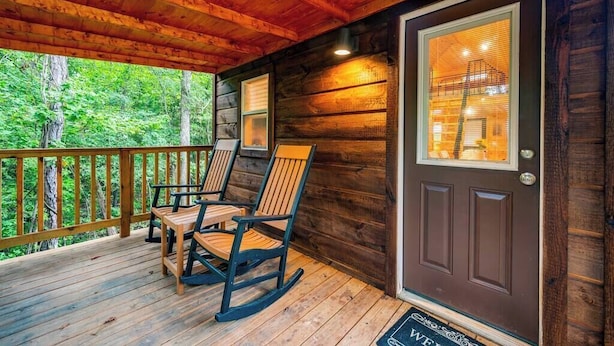 Eine hölzerne Veranda mit Schaukelstühlen und einer Tür mit Fenster.