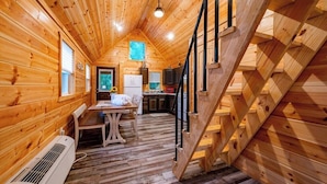 Ein Holzblockhaus-Interieur mit Essbereich, Küche und einer Treppe.