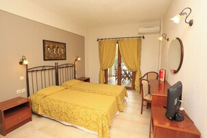 Un dormitorio con cama, mesitas de noche, un escritorio con computadora, una silla, un espejo y una ventana con cortinas.
