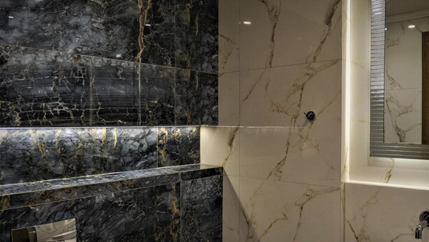 Un baño moderno con tocador de mármol, lavamanos y espejo.