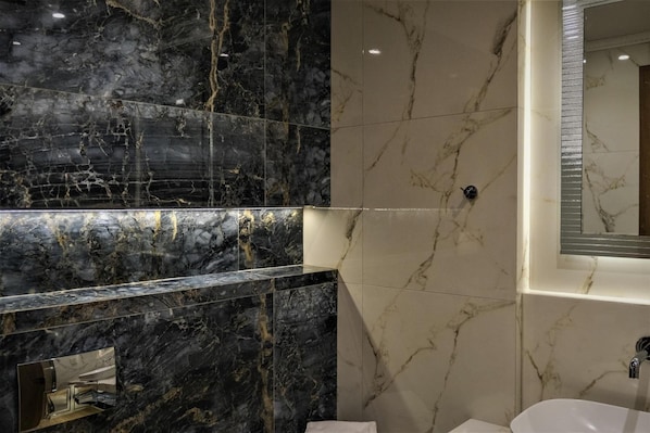 Un baño moderno con tocador de mármol, lavamanos y espejo.