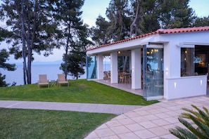 Ein modernes Haus mit Terrasse, Glasfenstern und Meerblick.