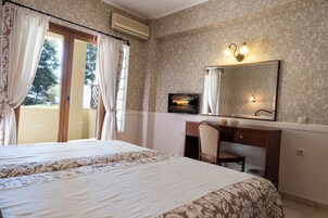 A hotel room with a large bed, a desk with a chair, a television, and a window with curtains.