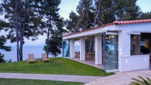 Uma casa moderna com terraço, portas de vidro e vista para o mar.
