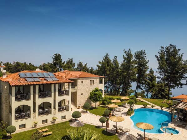 A building with a swimming pool, solar panels, and a well-maintained garden. - Country Inn (Kassandra)