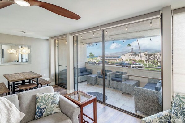 A spacious living area with a large sliding glass door leading to an outdoor patio with wicker furniture.