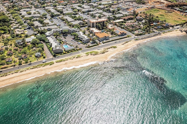 Stunning beachfront neighborhood with single-family homes and apartment buildings along a sandy beach.