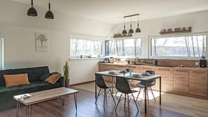 Moderni keittiö, jossa on puiset kaapit, ruokapöytä tuoleineen ja riippuvalaisimet.