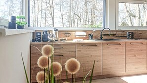 Moderni keittiö, jossa on puiset kaapit, pesuallas ja erilaisia kodinkoneita.