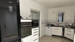 Eine moderne Küche mit einem schwarzen Kühlschrank, weißen Schränken und einem Geschirrspüler.
