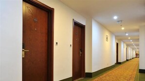 A hotel corridor with wooden doors, a patterned carpet, and a green carpeted area at the end. - Greentree Inn Yancheng Jianhu East Huiwen Road Columbus Square Business Hotel (Yancheng)
