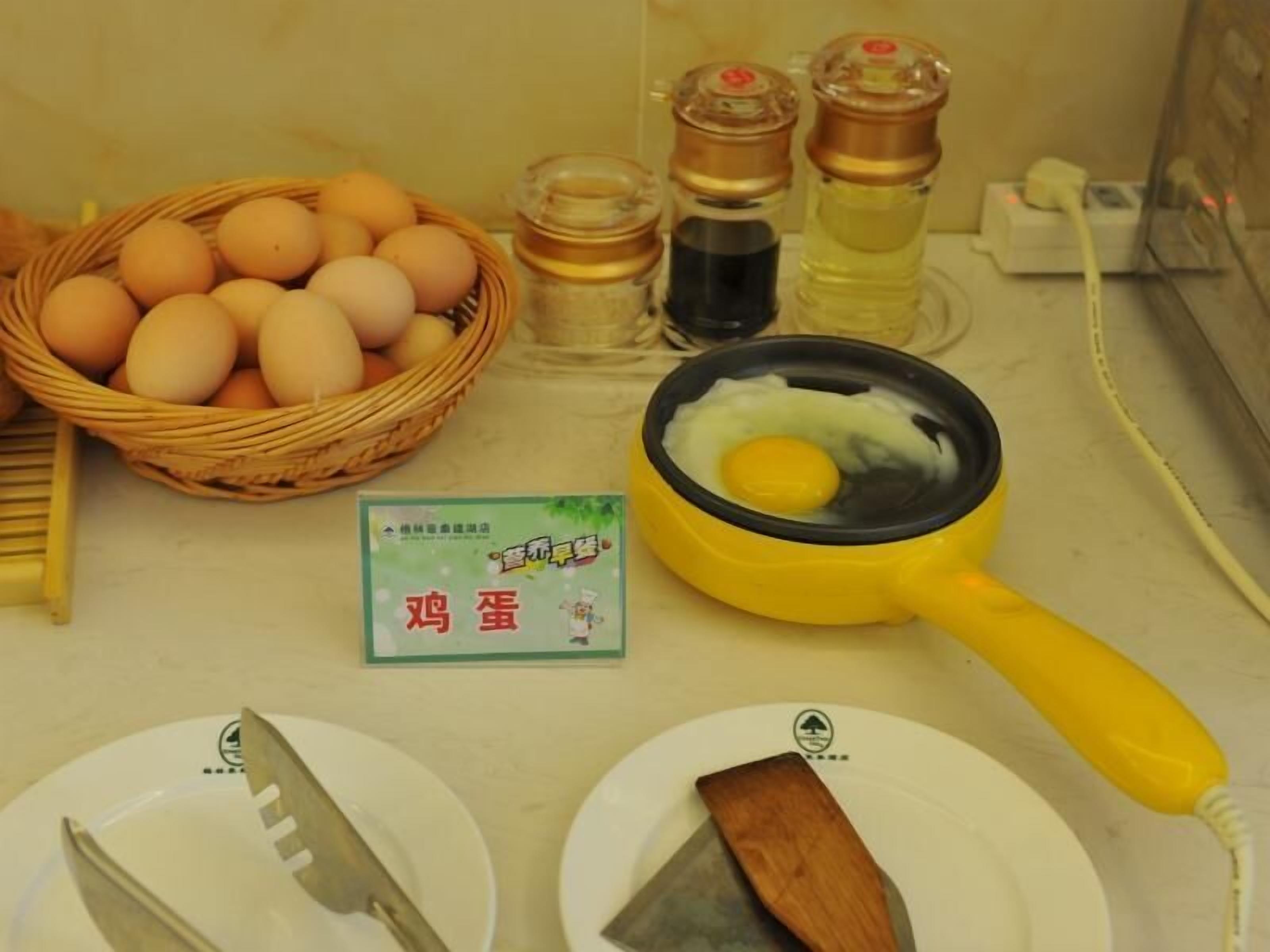 Un comptoir de cuisine avec un panier d’œufs, une poêle contenant un œuf, une spatule et une carte avec des caractères chinois.