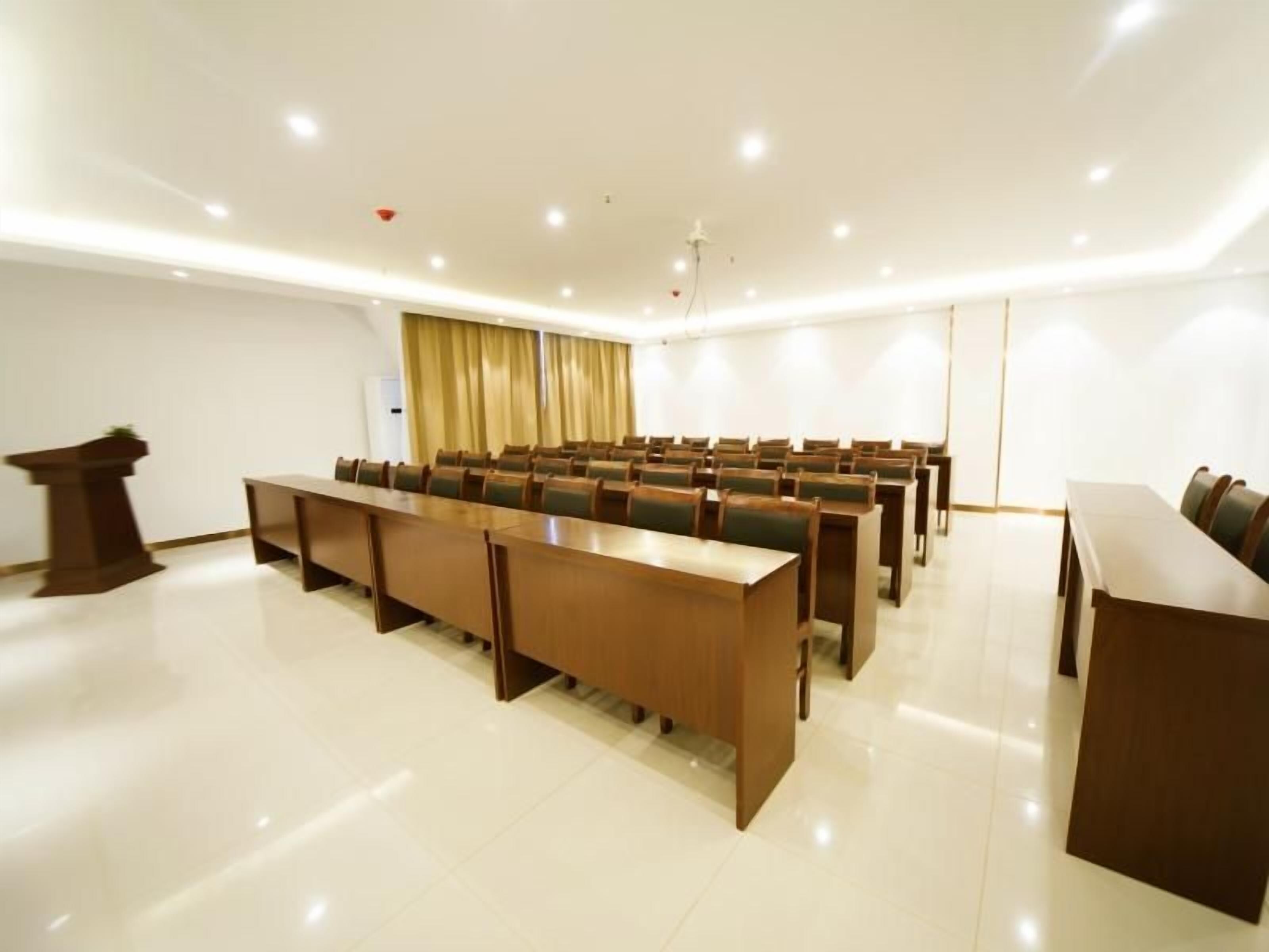 Un salón de conferencias con una larga mesa, sillas, un atril y una cortina.