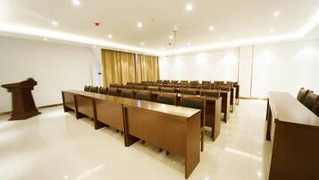 Un salón de conferencias con una larga mesa, sillas, un atril y una cortina.
