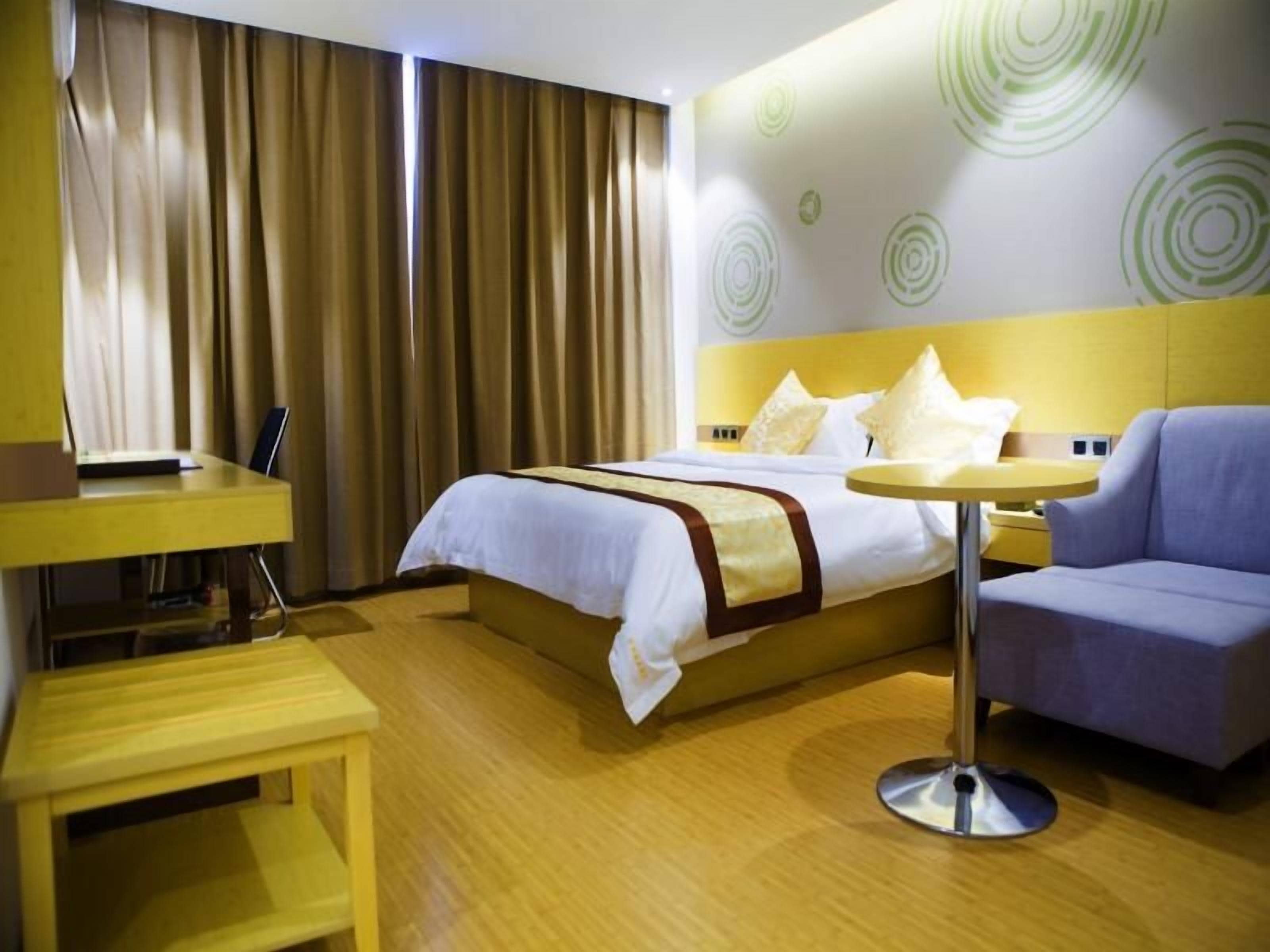 A hotel room with a bed, a desk, a chair, and a round table.