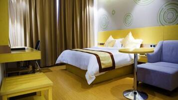 A hotel room with a bed, a desk, a chair, and a round table.
