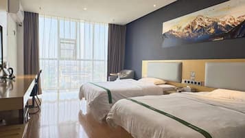 A hotel room with two beds, a desk, and a large window.