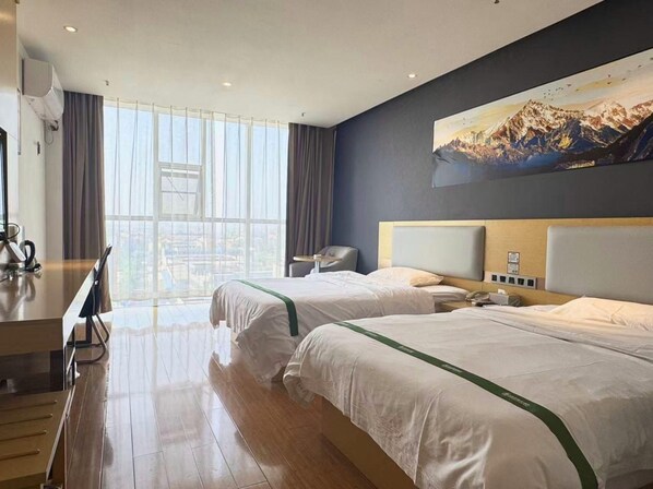 A hotel room with two beds, a desk, and a large window.