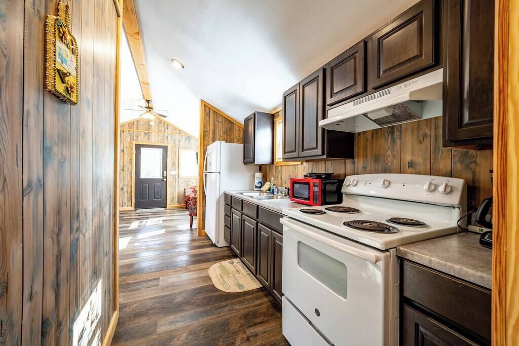 A kitchen with wooden cabinets, a white stove, and a microwave.