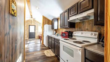 A kitchen with wooden cabinets, a white stove, and a microwave.