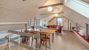 A cozy attic room with a wooden floor, a dining table with chairs, a sofa, and a bunk bed. - 3 bedroom gorgeous home in Højslev (Højslev)