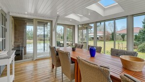 A spacious dining area with a wooden table, wicker chairs, and a large window offering a view of the outdoors. - 3 bedroom gorgeous home in Højslev (Højslev)