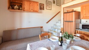 Ein Essbereich mit Tisch für vier Personen, einer Couch, Holzschränken und einer Treppe.
