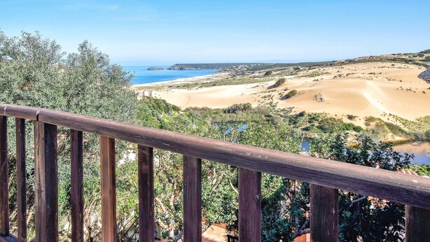 Eine Küstenlandschaft mit Sandstrand, blauem Himmel und einem Holzafence im Vordergrund.