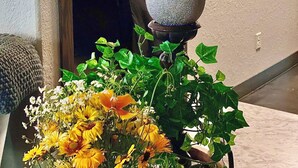 Une chambre avec un lit, un miroir, un mur orné d’une citation inspirante et un vase de fleurs.