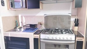 Ett kompakt kök med en gasspis, en mikrovågsugn och ett handfat.
