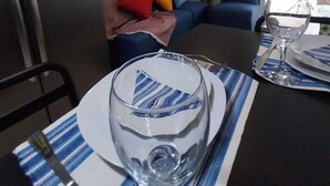 En matplats med ett bord dukat för två personer, ett kylskåp, en blå soffa med färgglada kuddar och inramade tavlor på väggen.