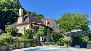 Ein Haus mit Schwimmbad, umgeben von Grünpflanzen und Bäumen.