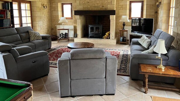 Ein gemütliches Wohnzimmer mit Kamin, zwei Sofas, einem Billardtisch und einem Fernseher.