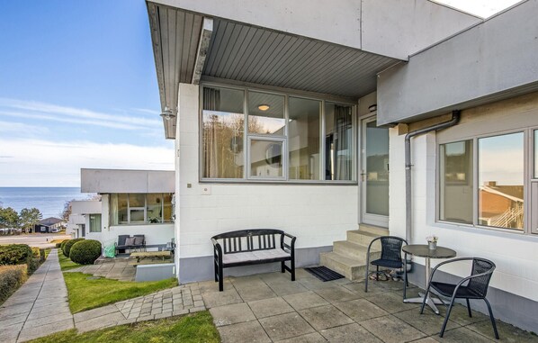 Un bâtiment moderne doté d’un patio comprenant un banc, deux chaises et une petite table.